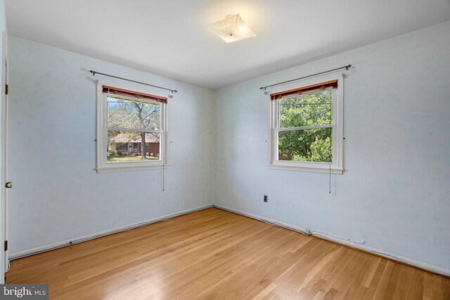 unfurnished room featuring a healthy amount of sunlight, baseboards, and wood finished floors