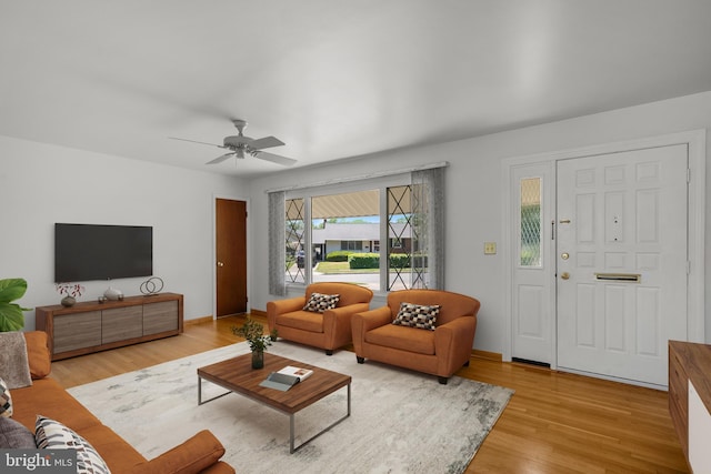 living room featuring ceiling fan, baseboards, and light wood-style floors