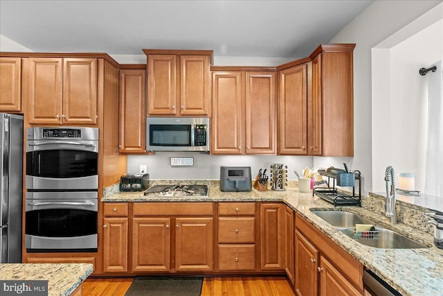10 Warbler Ct, Stafford, VA 22554 - kitchen with brown cabinetry, light stone countertops, a sink, stainless steel appliances, and light wood-style flooring