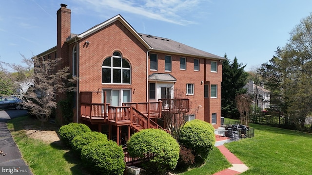 back of property with a deck, a chimney, brick siding, a lawn, and stairway