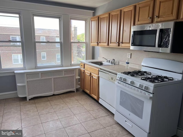 kitchen featuring light tile patterned flooring, a sink, white appliances, light countertops, and radiator heating unit