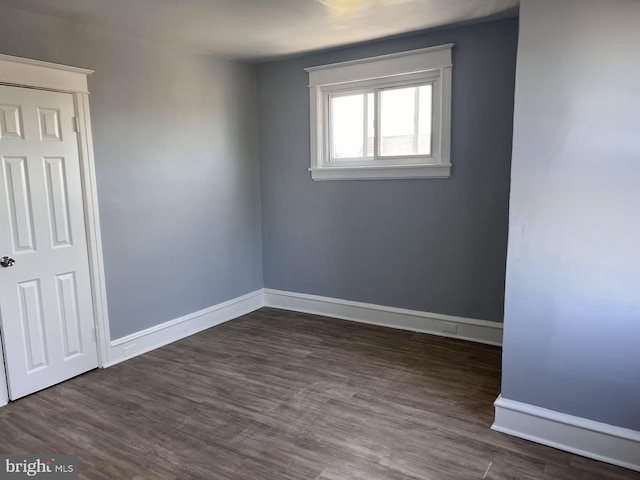 spare room with dark wood-type flooring and baseboards