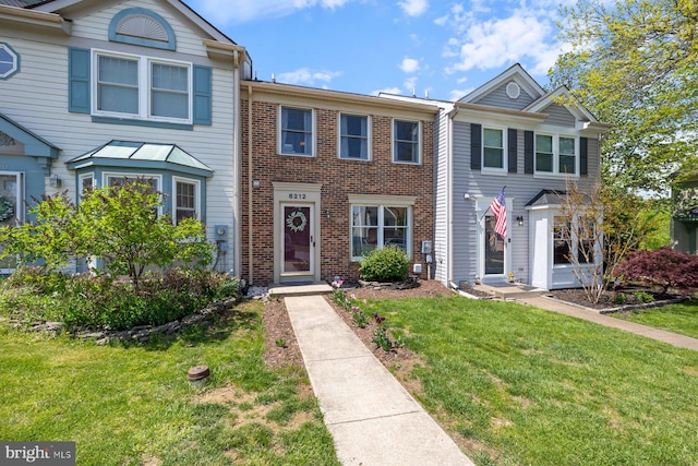 view of property featuring brick siding and a front yard