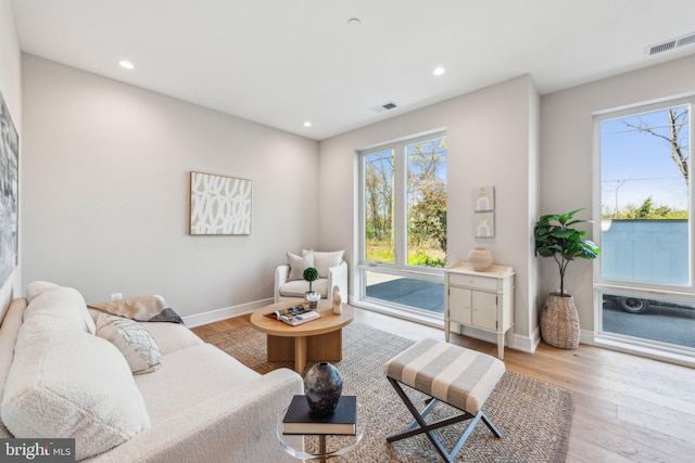 living room featuring visible vents, baseboards, wood finished floors, and a healthy amount of sunlight