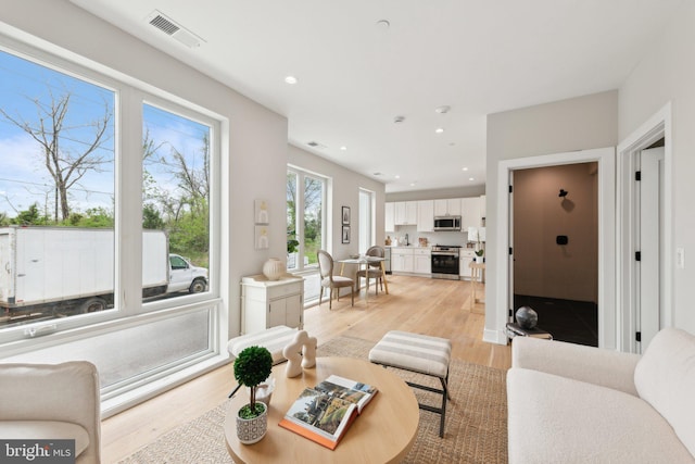 living area with recessed lighting, visible vents, and light wood-type flooring