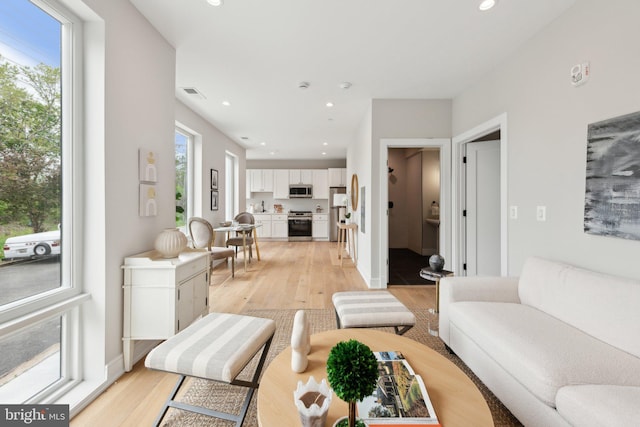 living room featuring a healthy amount of sunlight, recessed lighting, light wood-type flooring, and visible vents