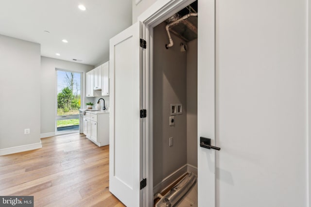 interior space featuring baseboards, recessed lighting, light wood finished floors, and a sink