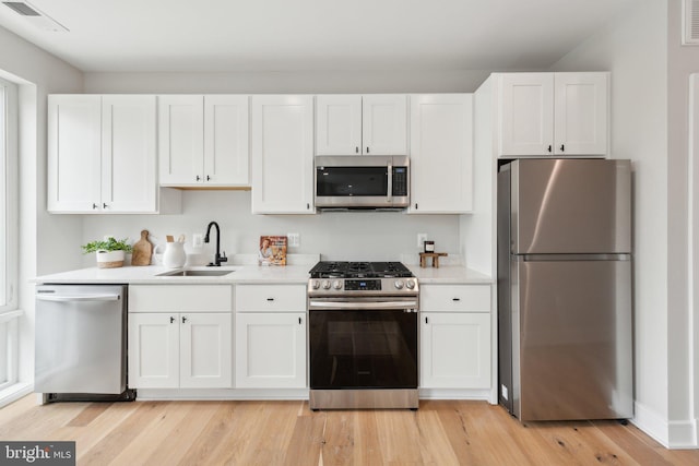 kitchen featuring light countertops, a sink, white cabinetry, and stainless steel appliances