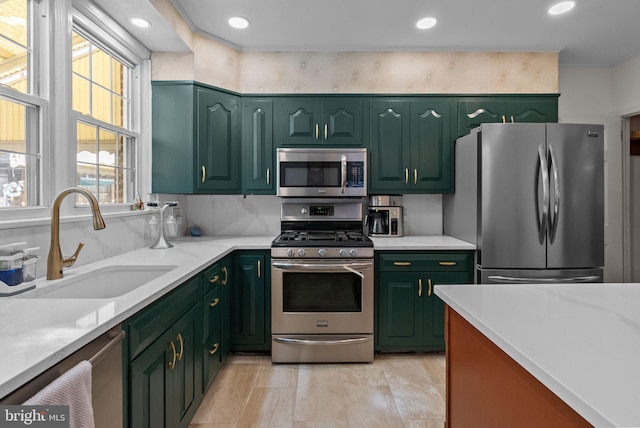 kitchen featuring recessed lighting, appliances with stainless steel finishes, a sink, and green cabinets