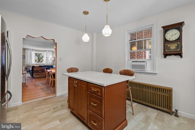 kitchen featuring hanging light fixtures, cooling unit, radiator, freestanding refrigerator, and a kitchen bar