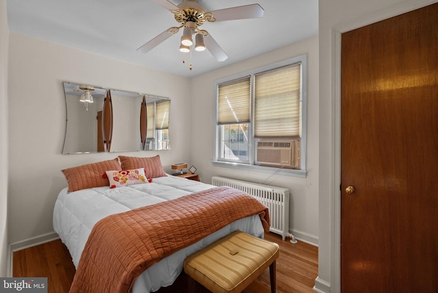bedroom featuring baseboards, a ceiling fan, radiator heating unit, and wood finished floors