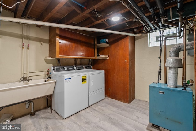 washroom featuring washing machine and clothes dryer, laundry area, a sink, and light wood-style flooring