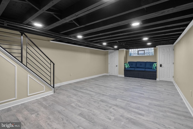 below grade area featuring baseboards, wood finished floors, and stairway