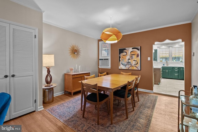 dining area featuring light wood-type flooring, ornamental molding, and baseboards