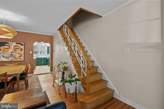 stairs with crown molding, baseboards, and wood finished floors