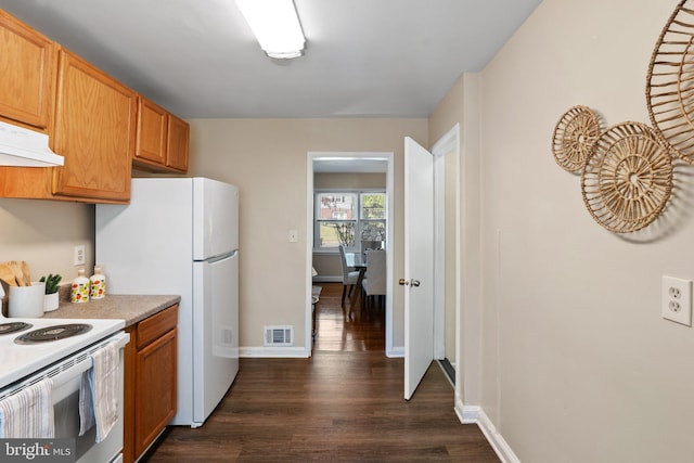kitchen with visible vents, dark wood-style flooring, white appliances, light countertops, and under cabinet range hood