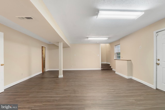 below grade area with visible vents, baseboards, wood finished floors, and stairway