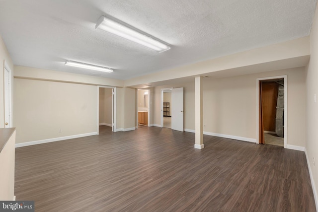finished basement featuring a textured ceiling, baseboards, and dark wood-type flooring