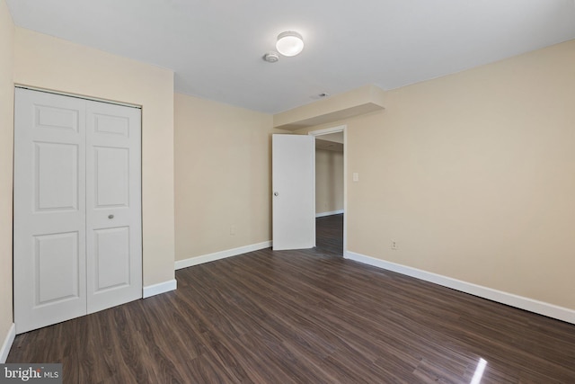 unfurnished bedroom featuring a closet, baseboards, and dark wood-type flooring
