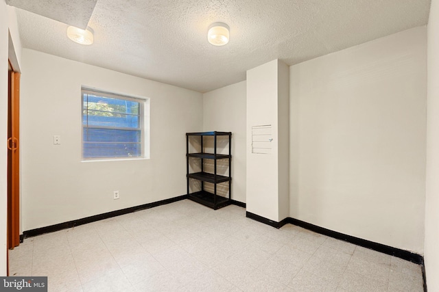 spare room featuring baseboards and a textured ceiling