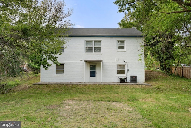 rear view of house featuring central air condition unit, fence, a yard, and brick siding