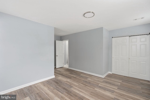 unfurnished bedroom featuring baseboards, visible vents, light wood-style flooring, and a closet