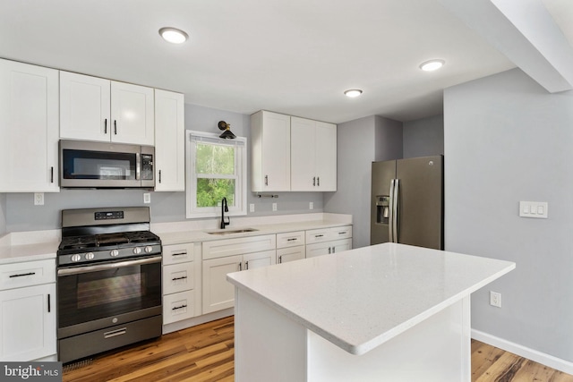 kitchen featuring white cabinets, appliances with stainless steel finishes, a sink, and light wood-style floors
