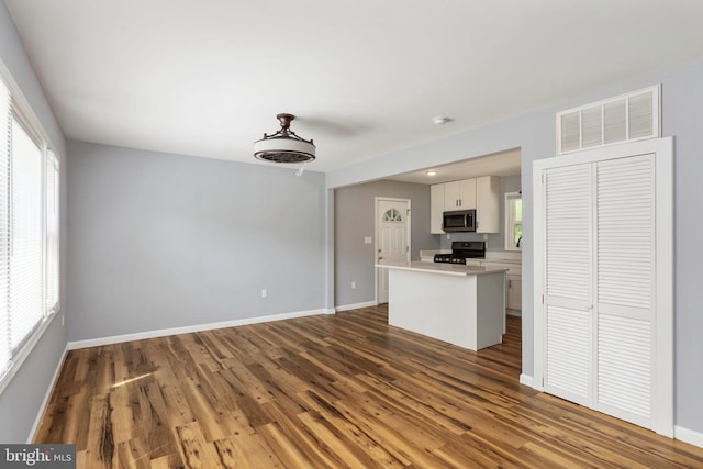 interior space with gas stove, baseboards, stainless steel microwave, and visible vents