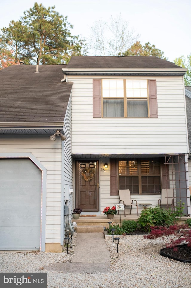 view of property featuring roof with shingles and an attached garage