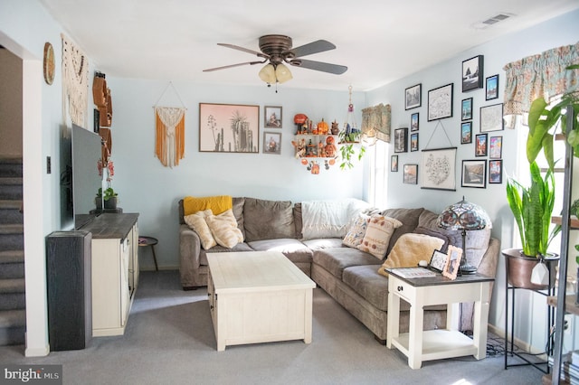 carpeted living area featuring stairway, a ceiling fan, and visible vents
