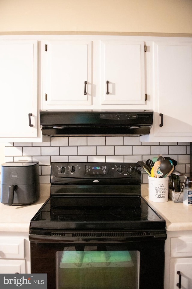 kitchen featuring decorative backsplash, electric range, range hood, light countertops, and white cabinetry