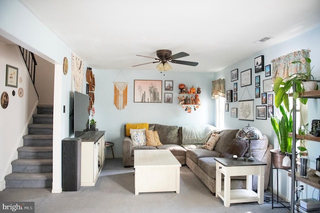 carpeted living room featuring stairs, a ceiling fan, and visible vents