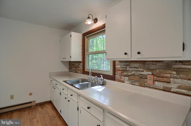 kitchen featuring a baseboard radiator, a sink, light countertops, white cabinetry, and tasteful backsplash