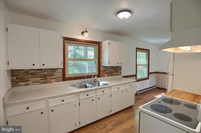 kitchen with white appliances, baseboard heating, white cabinetry, a sink, and light wood-style flooring