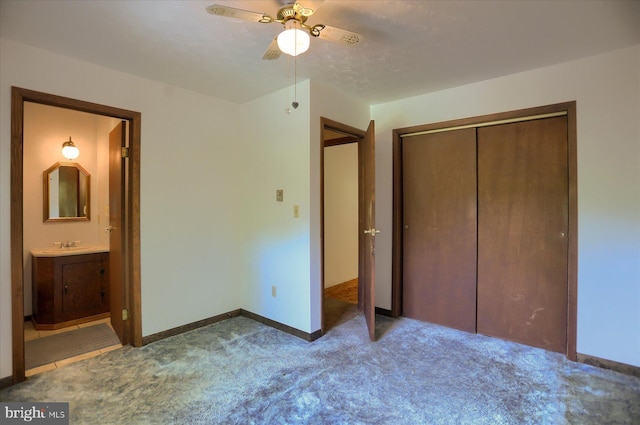 unfurnished bedroom with a sink, ensuite bath, carpet, baseboards, and a closet