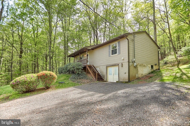 view of side of home featuring driveway and stairs