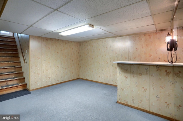 finished basement featuring baseboards, carpet, a paneled ceiling, and stairway
