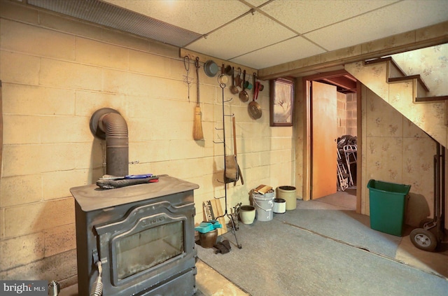 finished basement with a wood stove and a drop ceiling