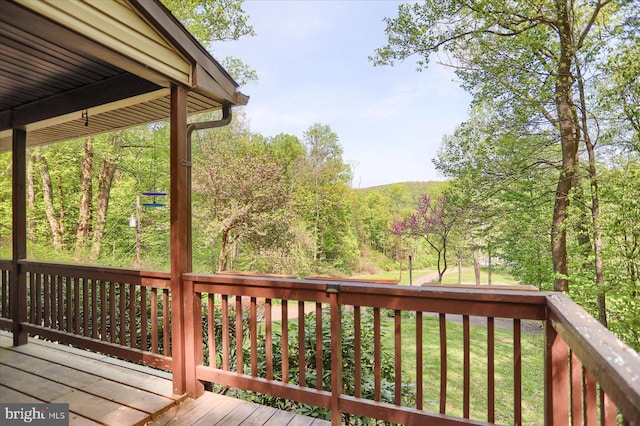 wooden deck with a view of trees and a yard