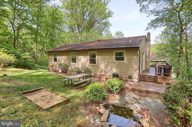 back of property featuring a lawn, a garden, a wooden deck, and a chimney