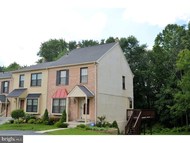 townhome / multi-family property with brick siding, a chimney, and a deck