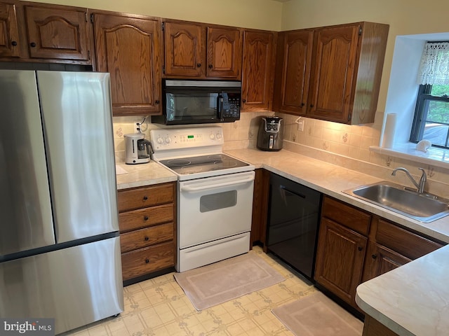 kitchen featuring light countertops, a sink, black appliances, and tasteful backsplash
