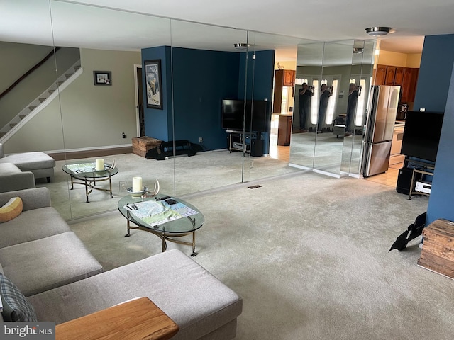 living room featuring stairway, baseboards, and light colored carpet