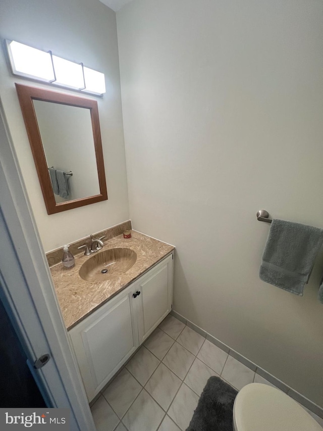 half bathroom with vanity, toilet, and tile patterned floors