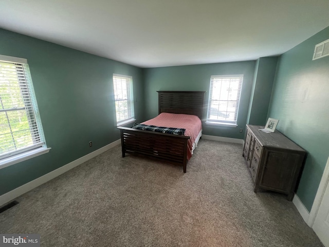 bedroom featuring carpet flooring, baseboards, visible vents, and multiple windows