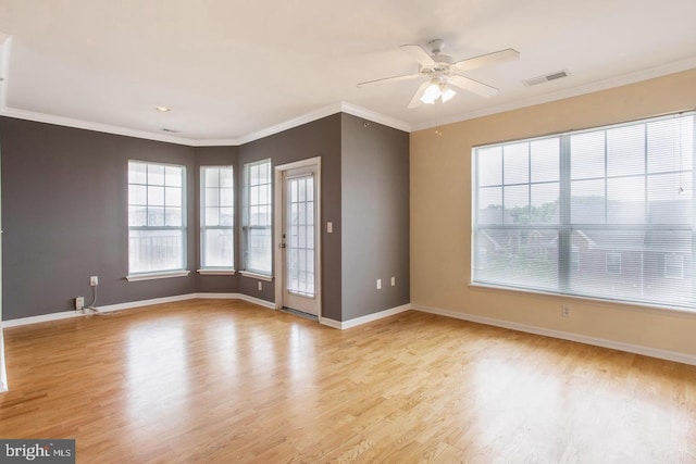 spare room featuring crown molding, baseboards, visible vents, and wood finished floors