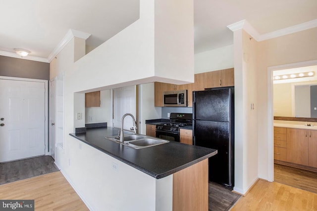 kitchen featuring crown molding, a peninsula, dark countertops, a sink, and black appliances