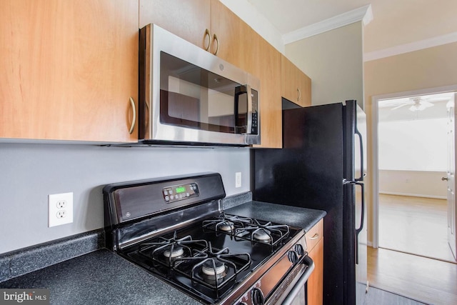 kitchen featuring crown molding, a ceiling fan, dark countertops, and stainless steel appliances