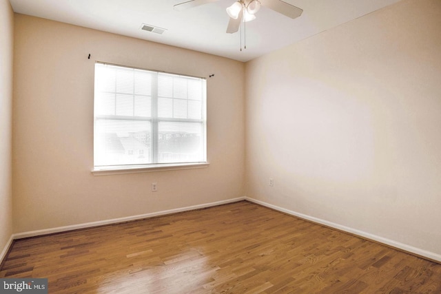 spare room with visible vents, a ceiling fan, baseboards, and wood finished floors