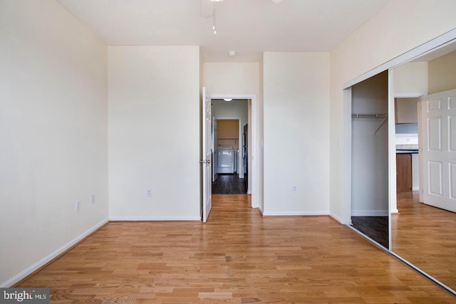 unfurnished bedroom with freestanding refrigerator, baseboards, light wood finished floors, and a closet